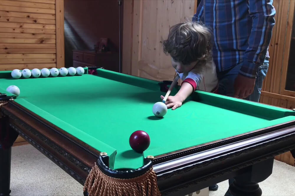 Мальчик играет в мини-бильярд Мальчик играет в мини-бильярд